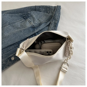 Spacious interior of beige crescent canvas bag with essentials like a phone and umbrella