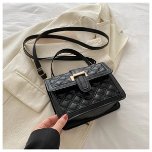 Close-up of black quilted texture and golden metal buckle on a small crossbody bag