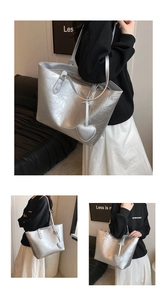 Detail of silver metallic tote bag featuring pleated texture and heart-shaped leather charm
