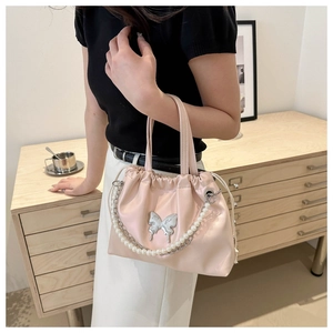 Detail of pink pleated bucket bag with pearl strap and silver butterfly ornament