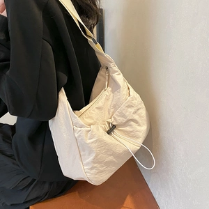 Cream nylon messenger bag for women featuring drawstring closure and adjustable strap