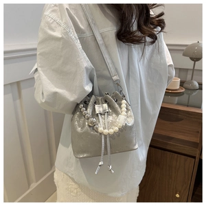 Silver beaded bucket bag with pearl handle and drawstring shown on a model