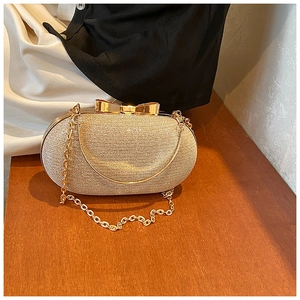 Close-up of golden glitter evening clutch with metallic bow clasp and chain strap