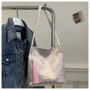 Détail du tissu jacquard floral rose avec étiquette en cuir et pendentif à pompon
