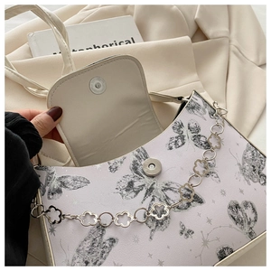 Detail of lavender shoulder bag featuring butterfly print and silver flower chain strap