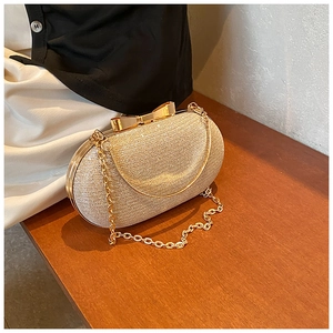 Macro detail of gold glitter evening clutch with bow-shaped metal clasp and chain strap