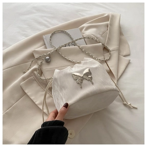 Détail du sac seau en satin blanc avec une grande boucle en métal argenté en forme de papillon