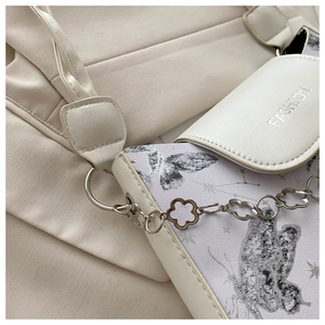 Detail of crossbody bag featuring butterfly print and fashion embossed logo on flap