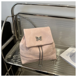 Detail of pink faux suede mini backpack featuring silver butterfly clasp and chain strap
