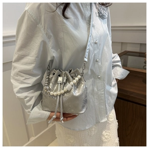 Détail d'un sac seau argenté avec chaîne en perles et fini métallisé sur un mannequin