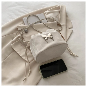 Détail du sac seau blanc à cordon avec papillon argenté et bandoulière chaîne