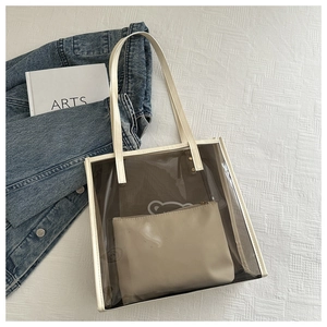 Détail d'un sac cabas transparent en PVC avec bordure crème et pochette intérieure assortie