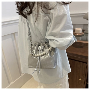 Silver bucket bag with crackled texture and pearl handle shown in a lifestyle setting