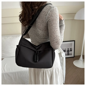Detail view of the black crossbody tote bag showing side woven drawstring and nylon texture