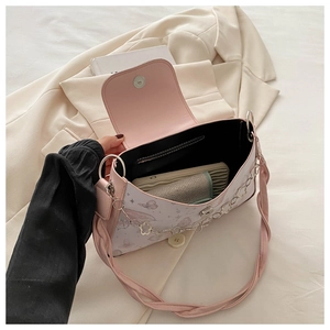 Detail of crossbody bag with floral print, silver chain, and interior zipper pocket
