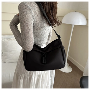 Detail of black oxford shoulder bag with woven knot accent and ruched side design