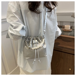 Silver bucket bag with large pearl and metal bead chain shown in a cafe setting