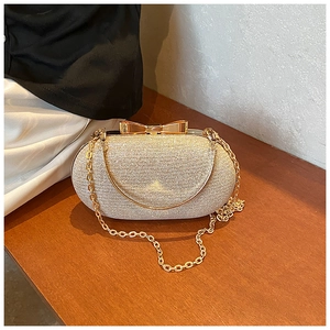 Detail of champagne gold glitter evening clutch with a metallic bow clasp and chain