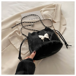 Detail of black drawstring bucket bag with marble texture and white butterfly charm