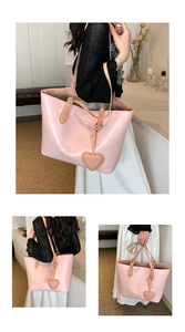 Pink oversized tote bag with heart charm detail and textured faux leather finish
