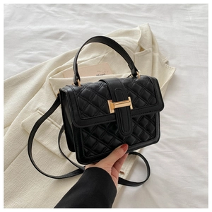Detailed view of black quilted leather handbag with premium gold clasp and chain strap