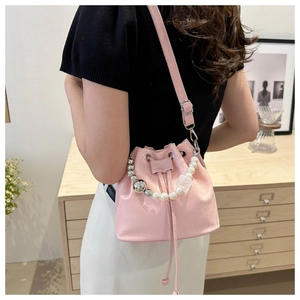 Pink bucket bag with pearl and metal bead handle shown in a lifestyle setting