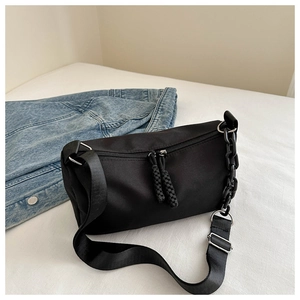 Detail of black cylinder canvas bag featuring dual zippers and stylish chain shoulder strap
