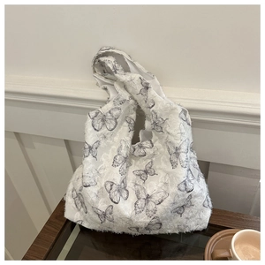 Detail of white textured fabric tote bag featuring vintage butterfly sketch and wood table