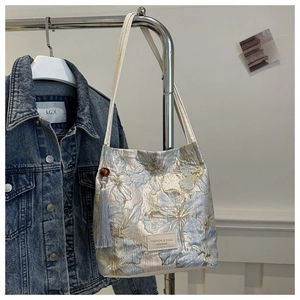 Vue détaillée de la broderie florale bleue avec anses en cuir et pompon gris
