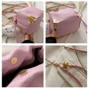 Detail of pink bucket bag featuring gold protective corners and adjustable chain strap