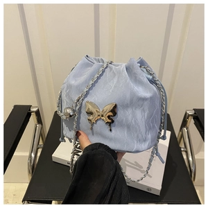 Close-up of light blue drawstring bucket bag with silver butterfly and chain strap