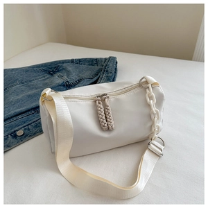 Detail of white nylon crossbody bag with woven rope pullers and plastic chain decoration