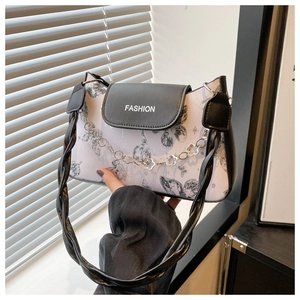 Detail of lavender bag with butterfly print, black leather flap and floral chain strap