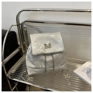 Detail of silver grey velvet mini backpack with metallic butterfly charm and chain