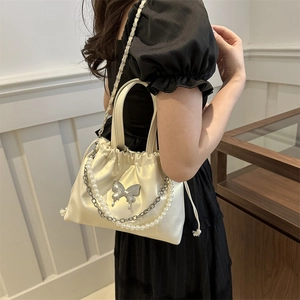 Elegant off-white satin bucket bag with pearl handle and silver butterfly buckle detail