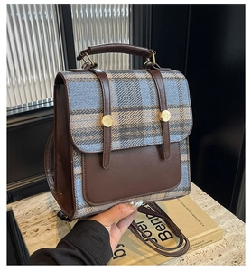 Detail view of British style plaid backpack with leather trim and gold metal buckles