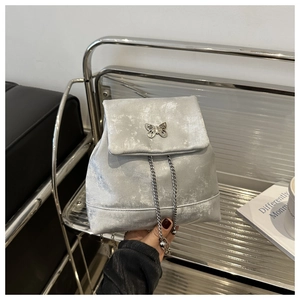 Detail of silver metallic textured backpack featuring butterfly ornament and chain strap