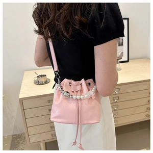 Détail du sac seau rose brillant avec poignée décorative en perles et perles argentées