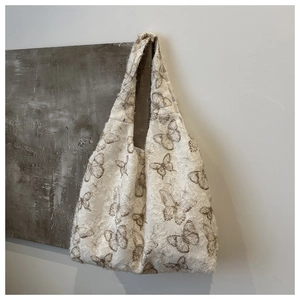 Detail of white canvas tote bag featuring brown butterfly patterns and fringed jacquard texture