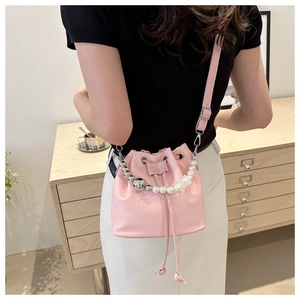 Sac seau en cuir rose avec poignée en perles et fermeture par cordon de serrage