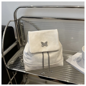 Close-up of velvet backpack with butterfly metal buckle and chain on metal stand