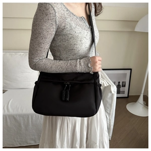 Detail of a large black nylon crossbody tote bag with adjustable shoulder strap