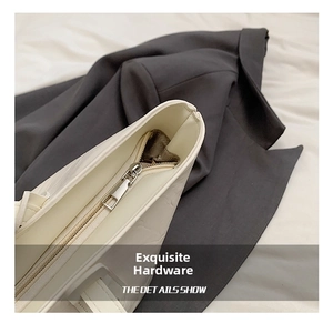 Detailed close-up of smooth silver zipper and premium leather texture on white tote bag
