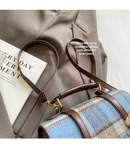 Close-up of British style checkered wool handbag with brown leather trim and gold buckle