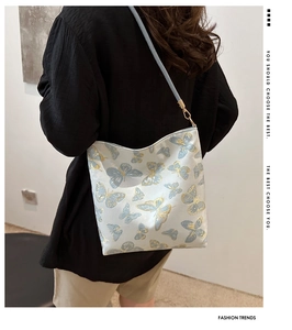 Détail de la broderie de papillon doré sur un sac à bandoulière en soie bleu clair