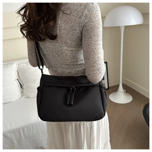 Close-up of black nylon dumpling tote bag with woven knots and adjustable strap