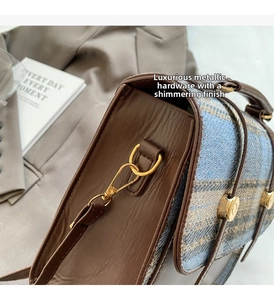 Detail of high-gloss gold D-ring hardware and tweed fabric on a leather backpack