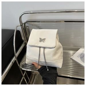 Detail of white mini backpack featuring silver butterfly metal buckle and chain decoration