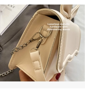 Detail of cream chain crossbody bag with bow decoration and gold metal hardware