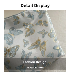 Gros plan du tissu jacquard bleu clair avec des détails de broderie papillon dorée